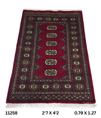 Handmade wool and cotton area rug or runner with repeated geometric Bokhara pattern displayed on floor