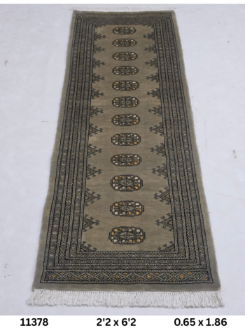 Handmade wool and cotton area rug or runner with repeated geometric Bokhara pattern displayed on floor