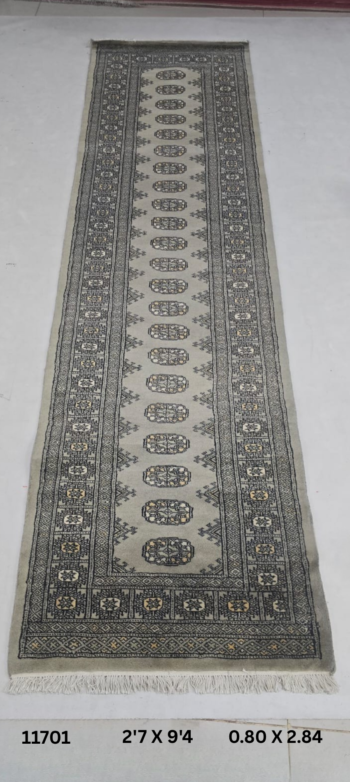 Handmade wool and cotton area rug or runner with repeated geometric Bokhara pattern displayed on floor