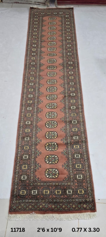 Handmade wool and cotton area rug or runner with repeated geometric Bokhara pattern displayed on floor