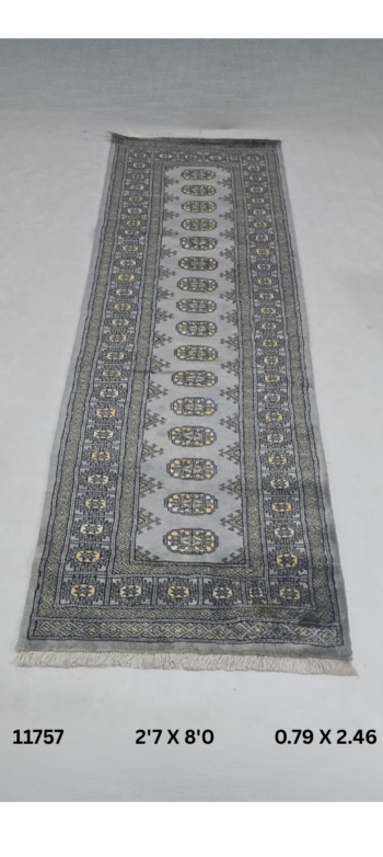 Handmade wool and cotton area rug or runner with repeated geometric Bokhara pattern displayed on floor
