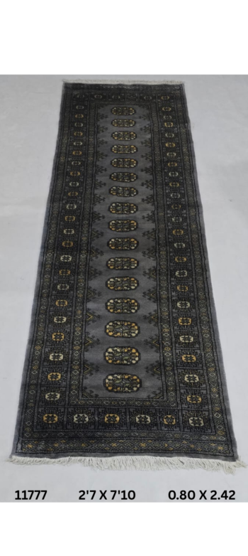 Handmade wool and cotton area rug or runner with repeated geometric Bokhara pattern displayed on floor