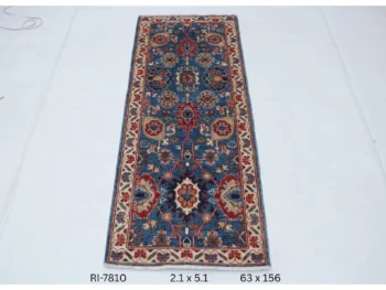 Handmade wool and cotton area rug or runner with classic floral Heriz pattern displayed on floor