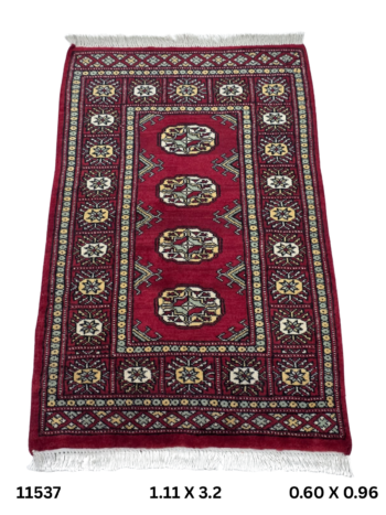Handmade wool and cotton area rug or runner with repeated geometric Bokhara pattern displayed on floor