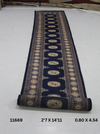 Handmade wool and cotton area rug or runner with repeated geometric Bokhara pattern displayed on floor