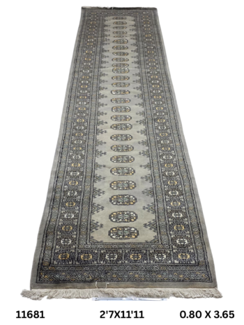 Handmade wool and cotton area rug or runner with repeated geometric Bokhara pattern displayed on floor