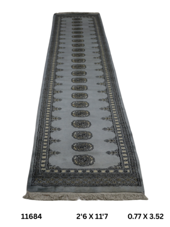 Handmade wool and cotton area rug or runner with repeated geometric Bokhara pattern displayed on floor